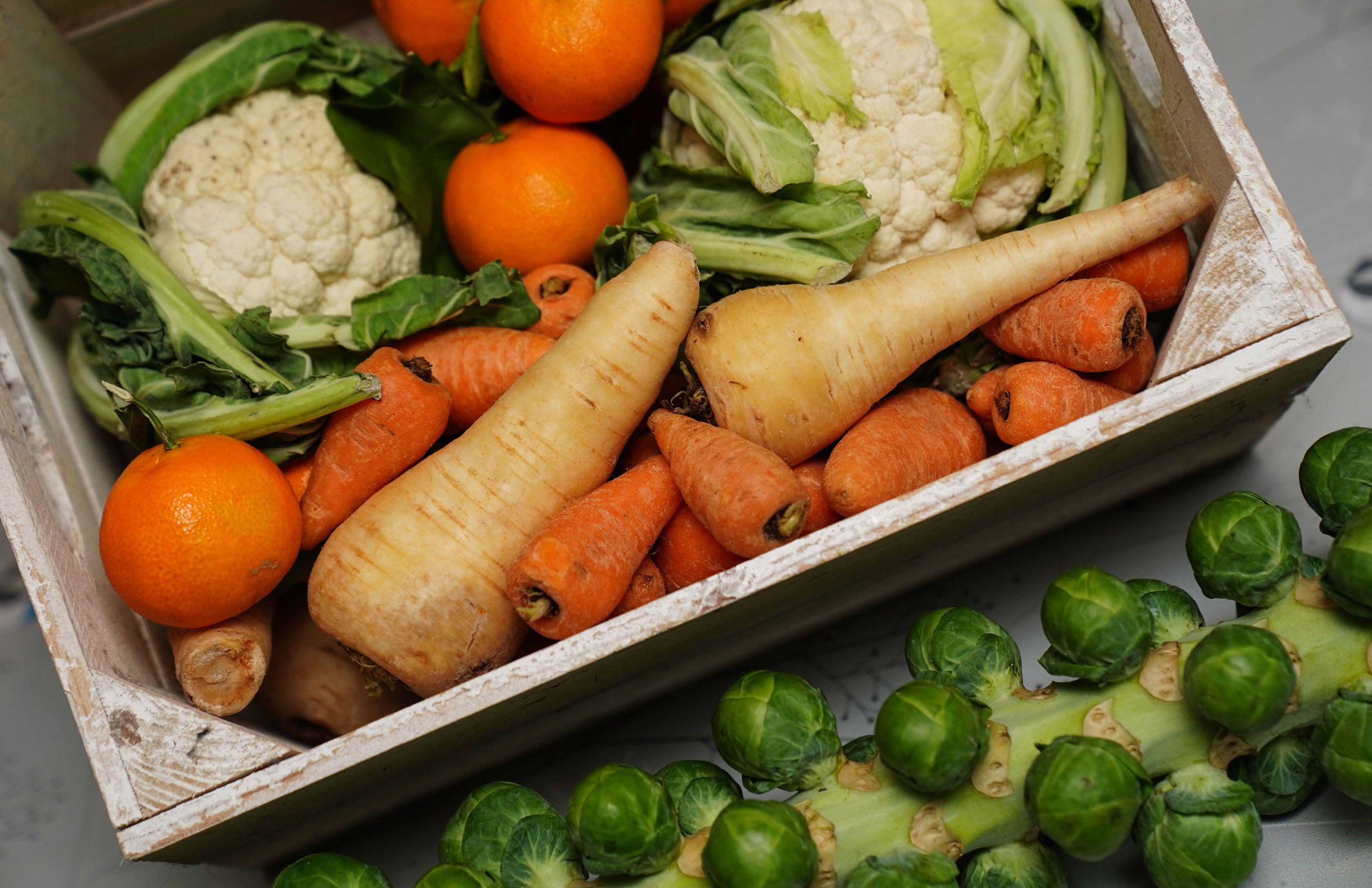 A basket of fruit and vegetables laid out on a table.