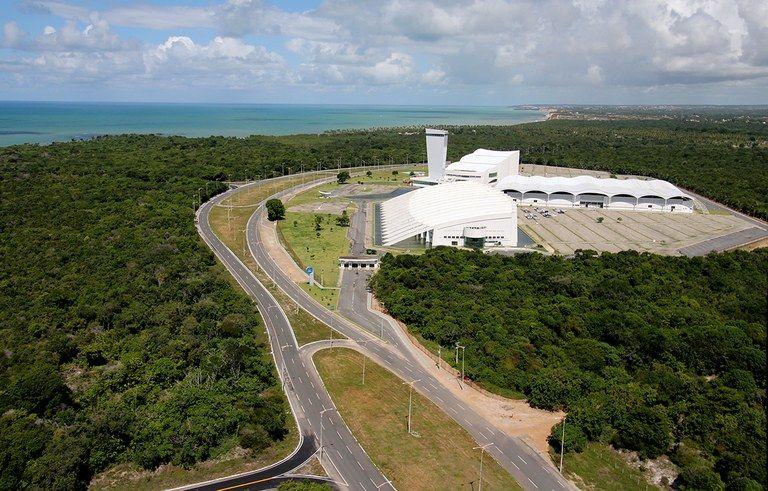 Foto aérea de uma avenida cercada por floresta e um prédio