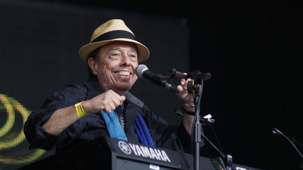 Foto mostra idoso branco sorrindo em frente a um teclado