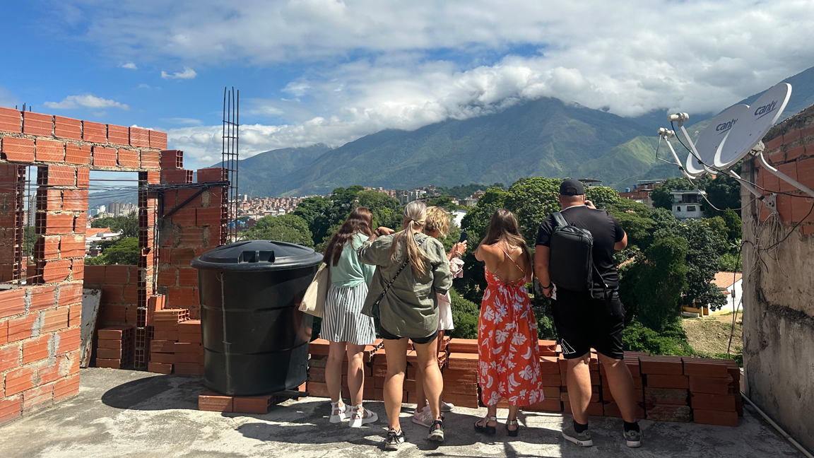 Los turistas rusos en una vivienda a medio construir en Petare y con la cordillera del Ávila al fondo.