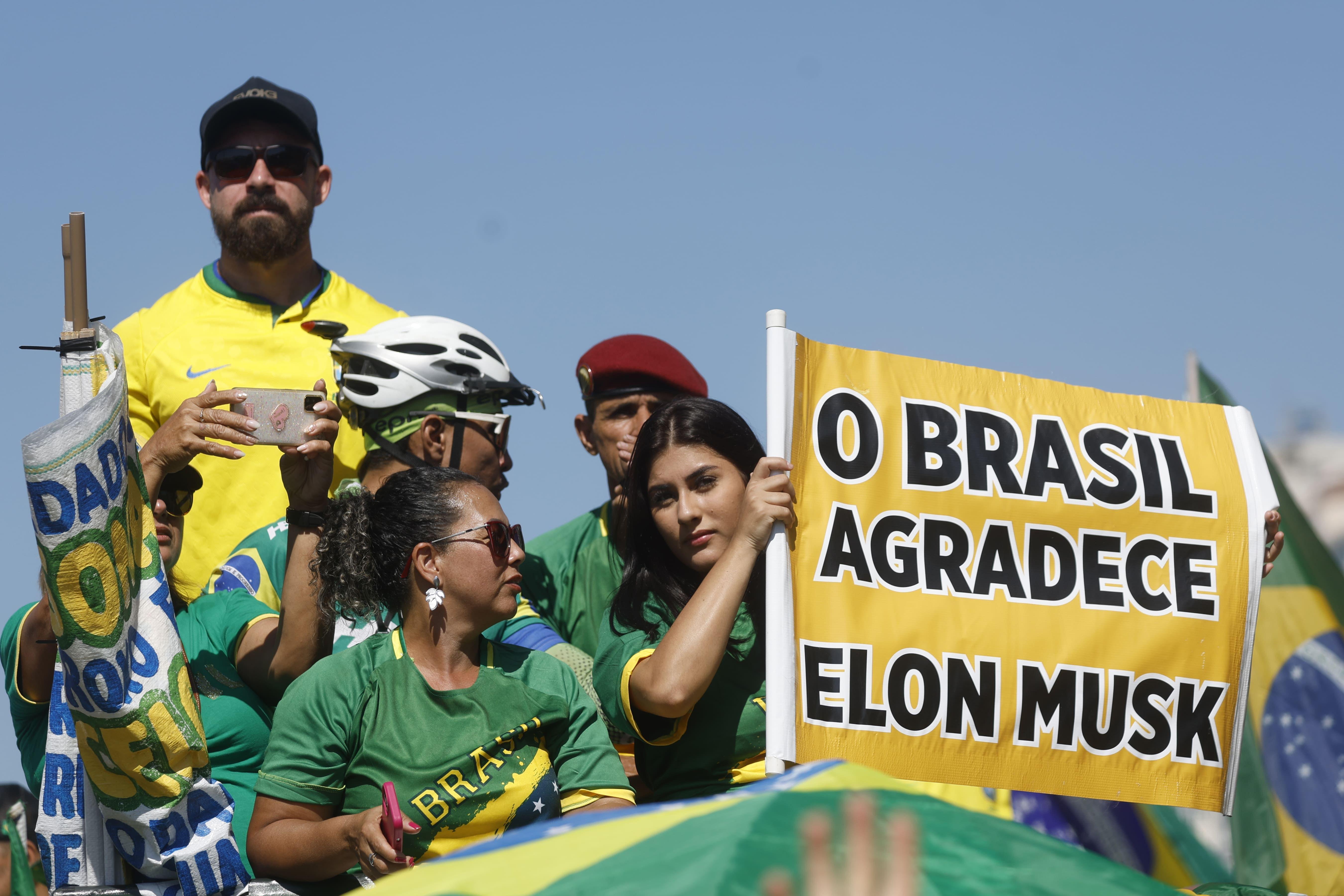 Apoiadores de Bolsonaro seguram um cartaz agradecendo Elon Musk