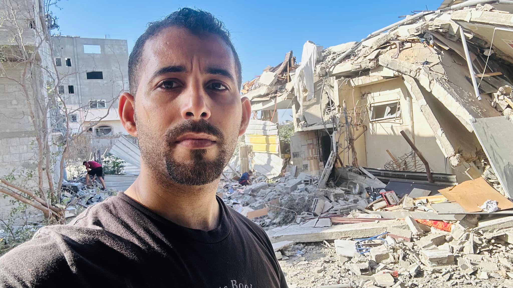 الشاعر الفلسطيني مصعب أبو توهة أمام منزله المهدم في قطاع غزة 