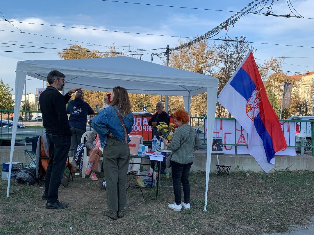 Muškarci i žene stoje okupljeni ispred mosta