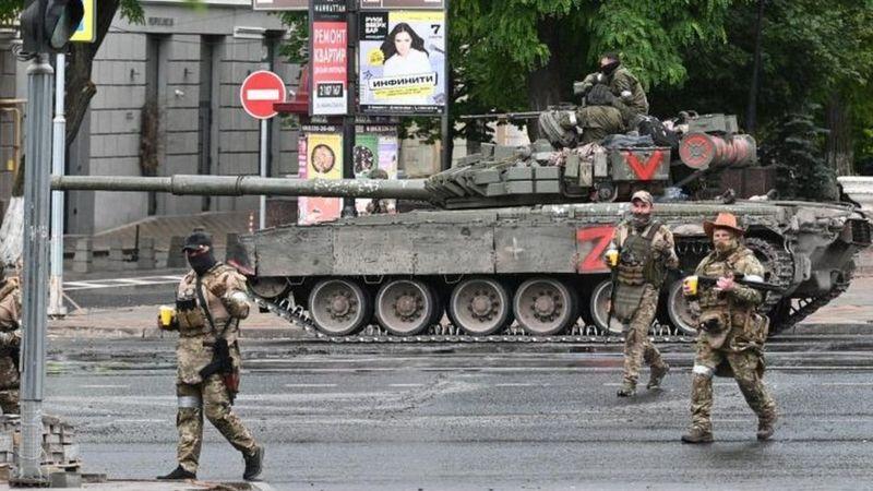 Membros do Grupo Wagner ao lado de tanque de guerra