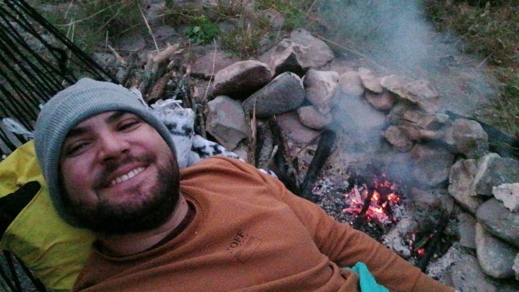 Homem deitado e sorrindo, deitado ao lado de fogueira