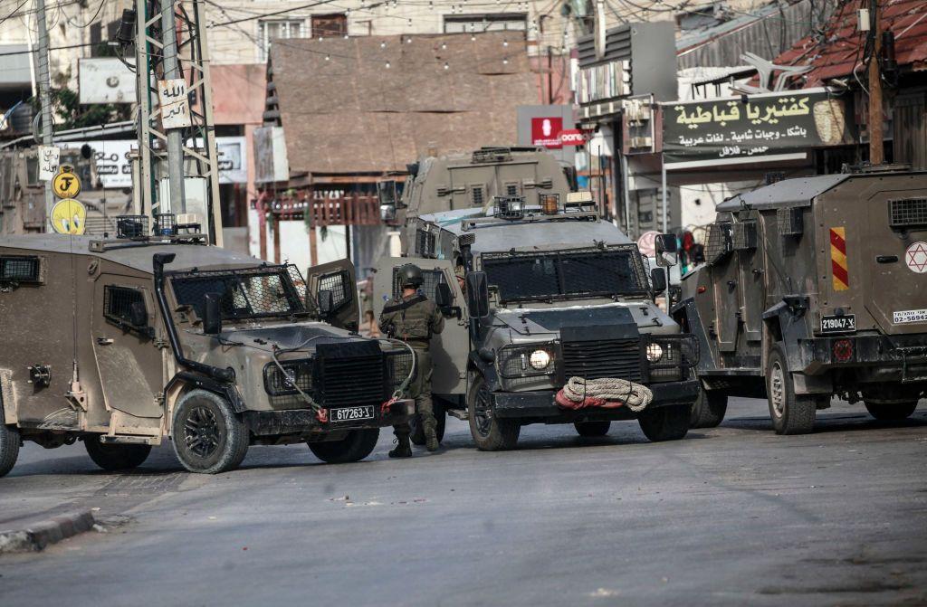 Um soldado entre vários veículos militares em Qabatiya, na Cisjordania