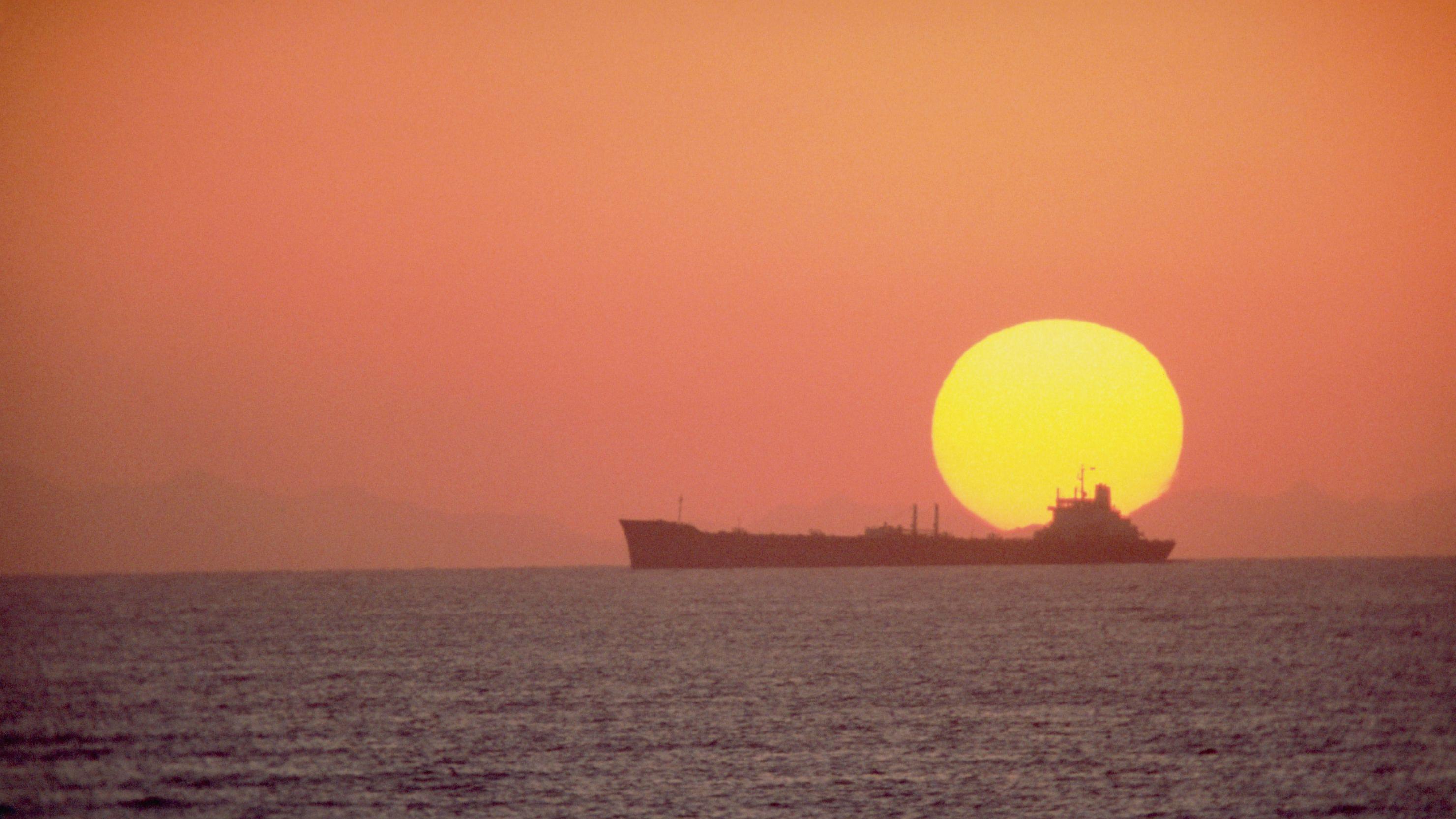 An oil tanker silhouetted against the setting sun in the South China Sea