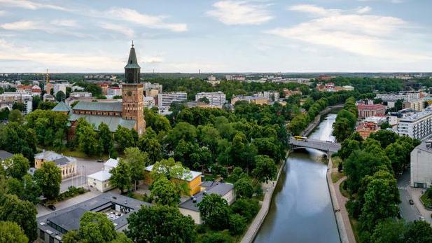 Vista aérea del río Aura y la catedral de Turku, entre árboles y edificios.