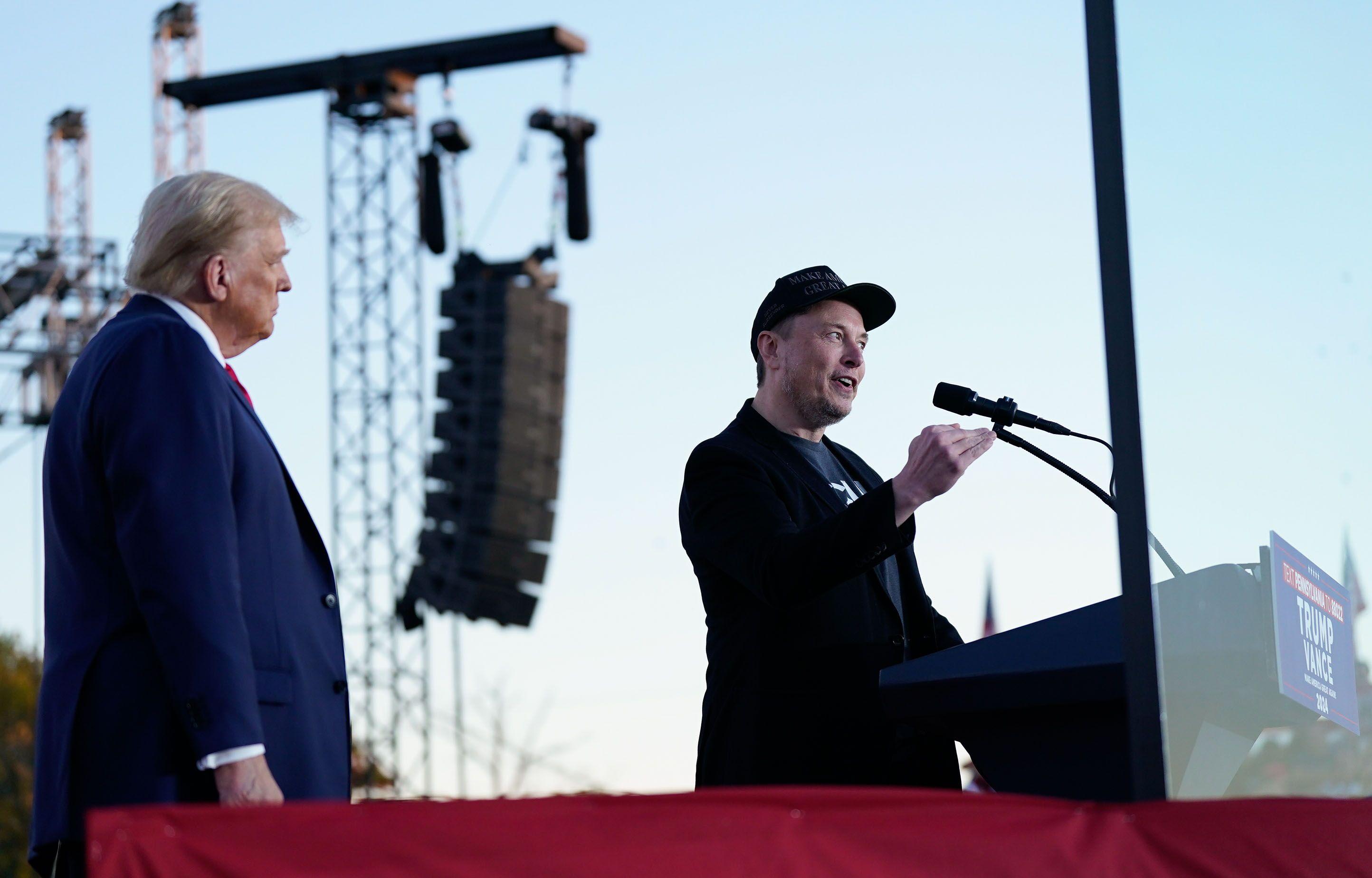 Donald Trump observando Elon Musk discursar durante comício em Butler, na Pensilvânia, em 5 de outubro de 2024