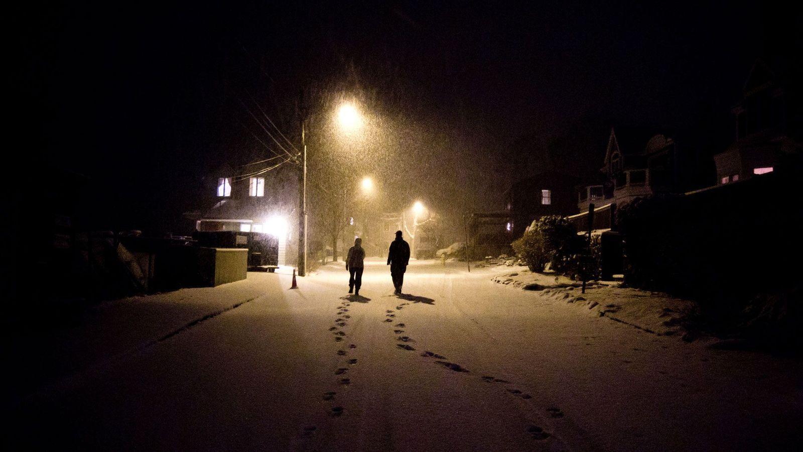 Dos personas caminando en la nieve por una ciudad