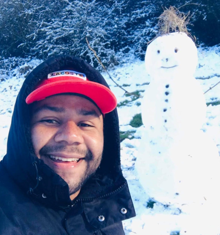 Selfie de Lucas dos Anjos, trabalhador de frigorífico brasileiro na Irlanda, com boneco de neve atrás