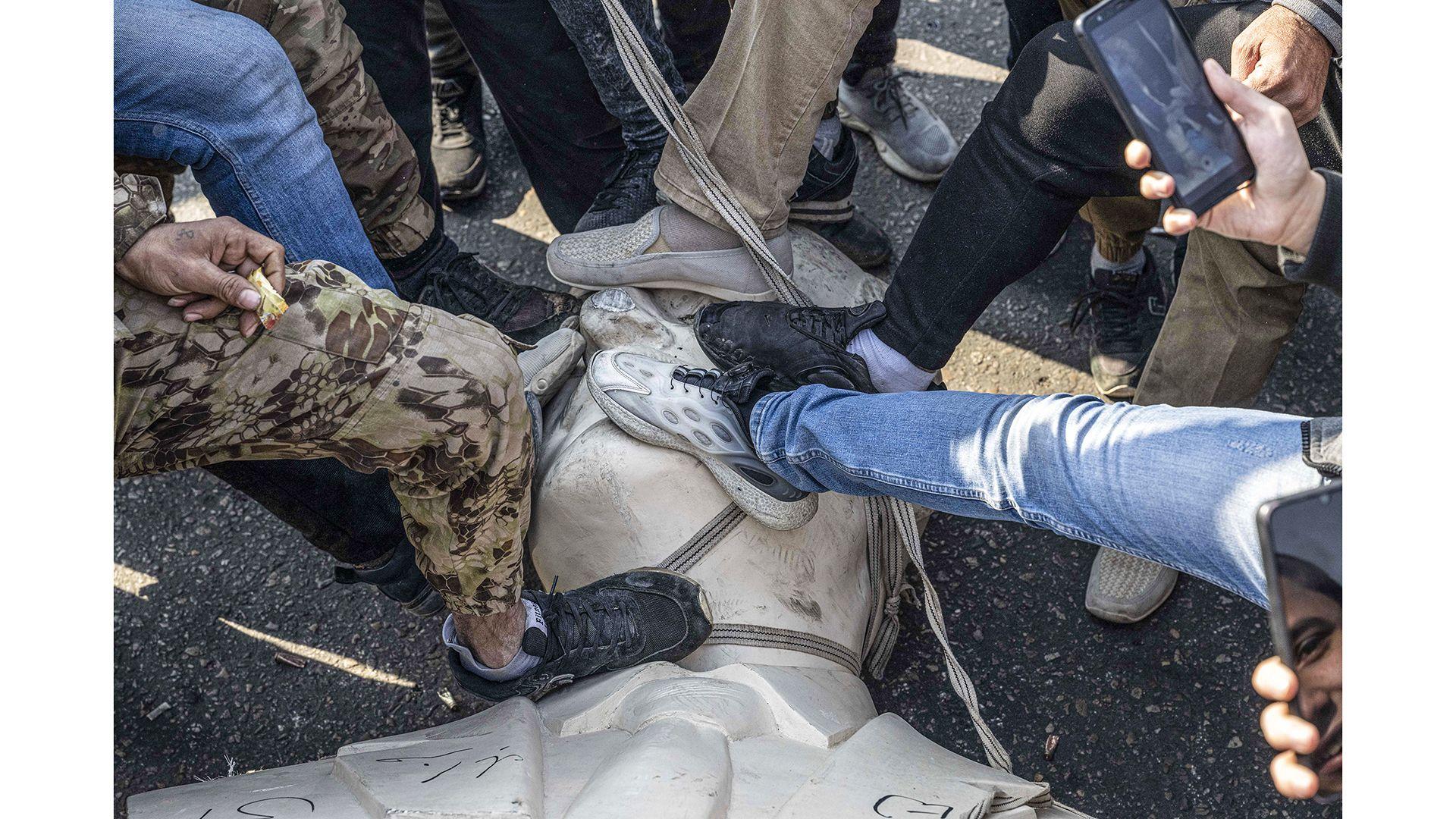 Manifestantes pisotean la estatua derribada de Hafez al Asad