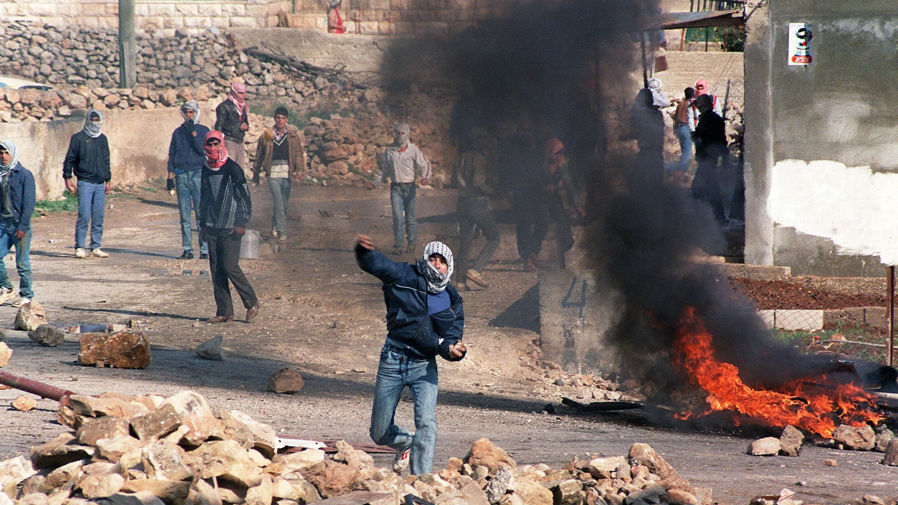 متظاهرون فلسطينيون يلقون الحجارة على شرطة مكافحة الشغب الإسرائيلية شمال القدس، في 21 كانون الأول/ديسمبر 1987.