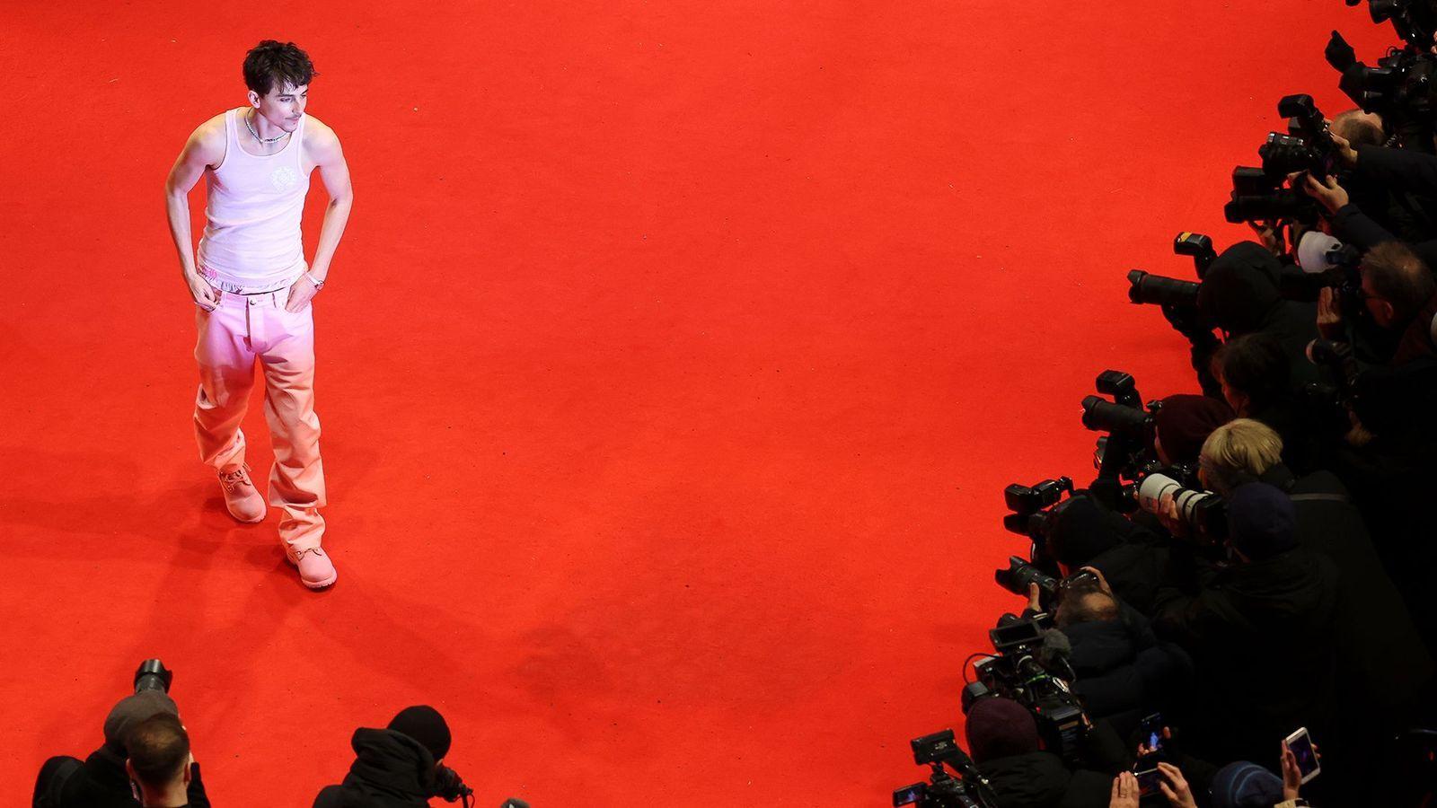Chalamet no tapete vermelho do Festival de Cinema de Berlim, na Alemanha. Ele está usando uma calça e uma blusa regata rosa claras.