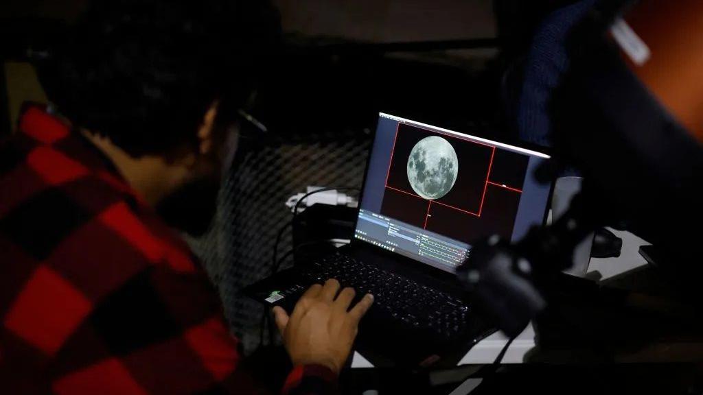 علماء ينظرون إلى القمر على شاشة في مرصد فوستر في عاصمة تشيلي سانتياغو