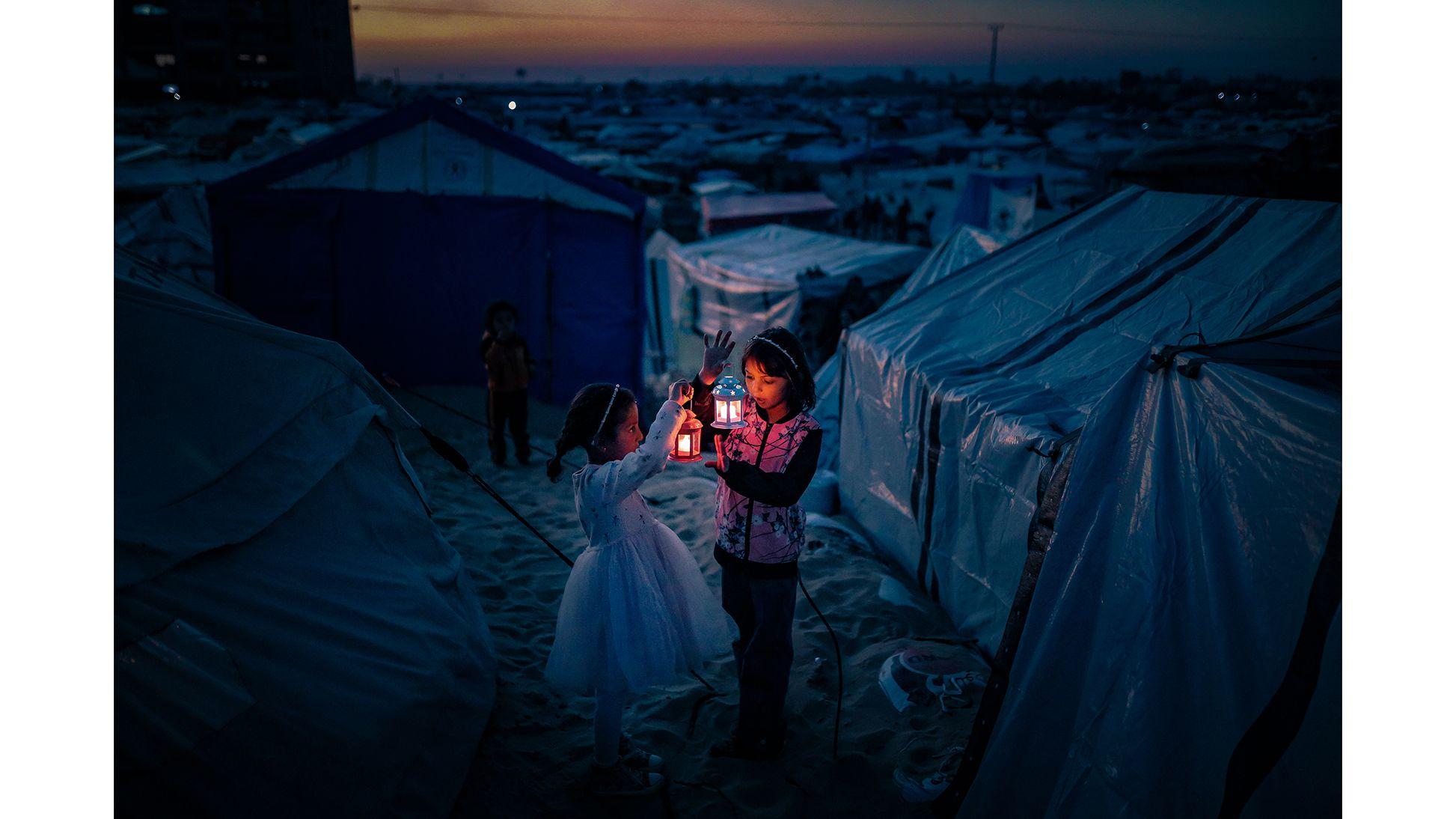 Dos niñas con linternas en un campo de refugiados de Gaza