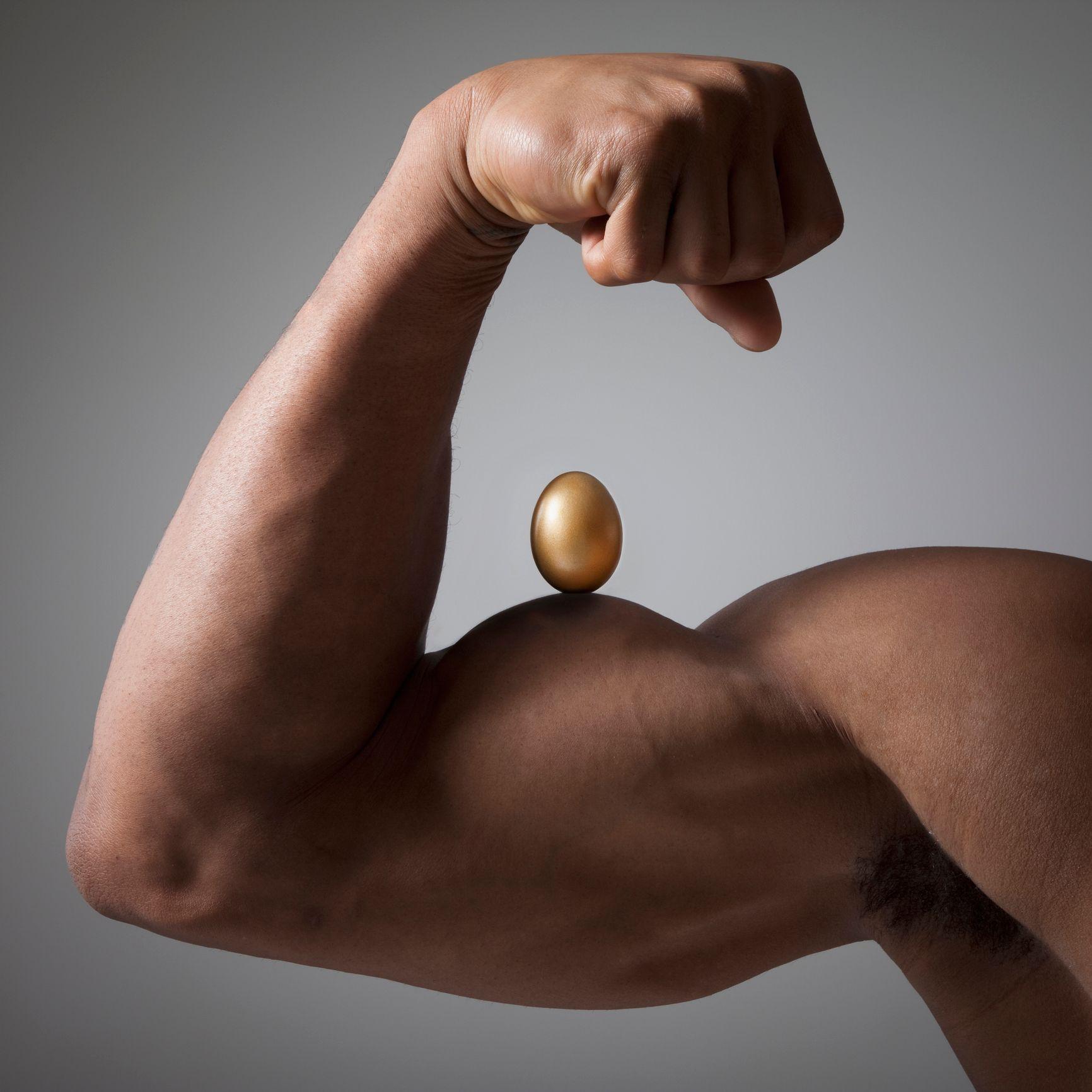 Imagem de homem com braço musculoso com um ovo em cima do bíceps 