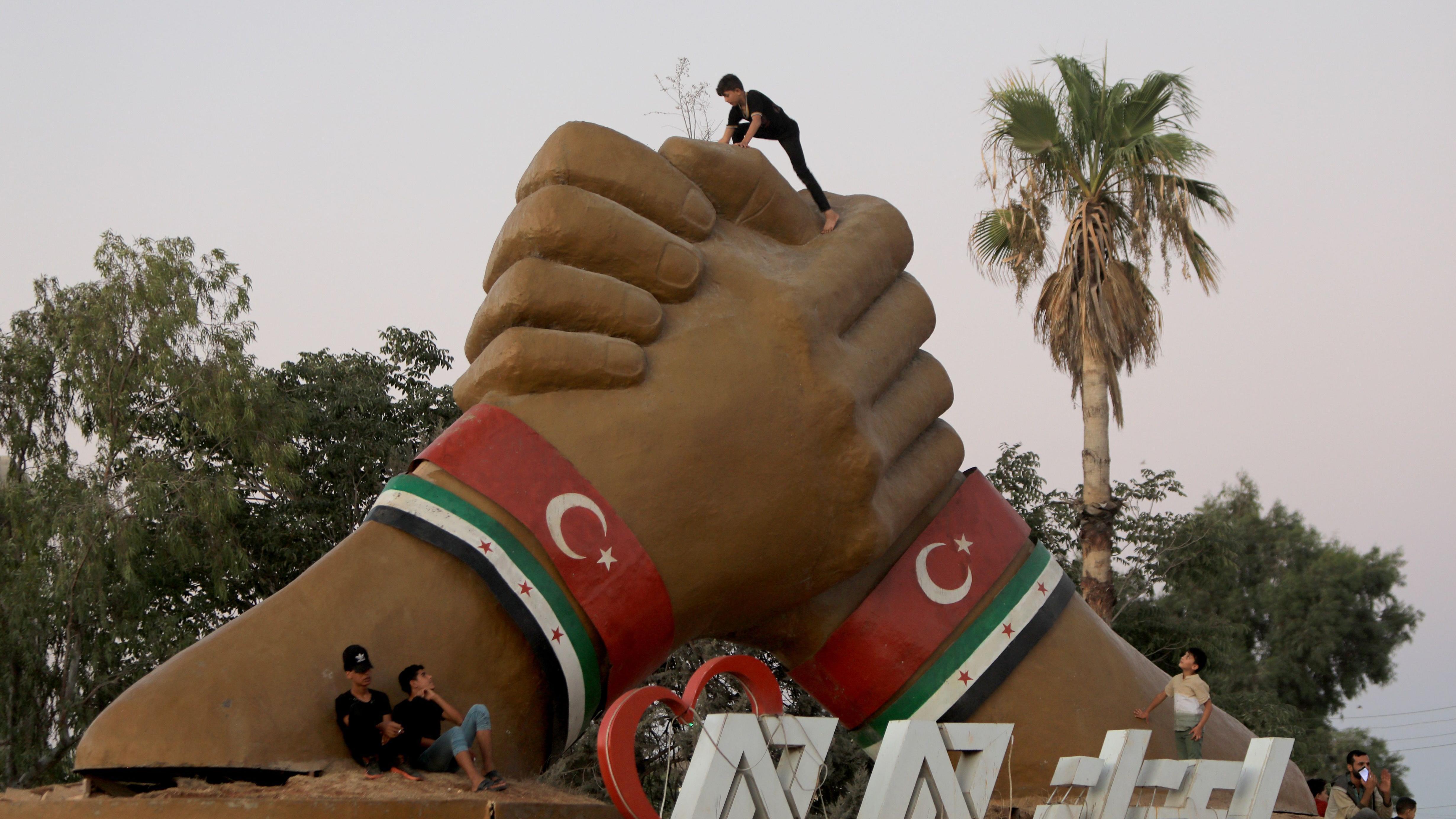 أطفال يلعبون حول نصب تذكاري للتضامن بين تركيا وقوات المعارضة السورية 