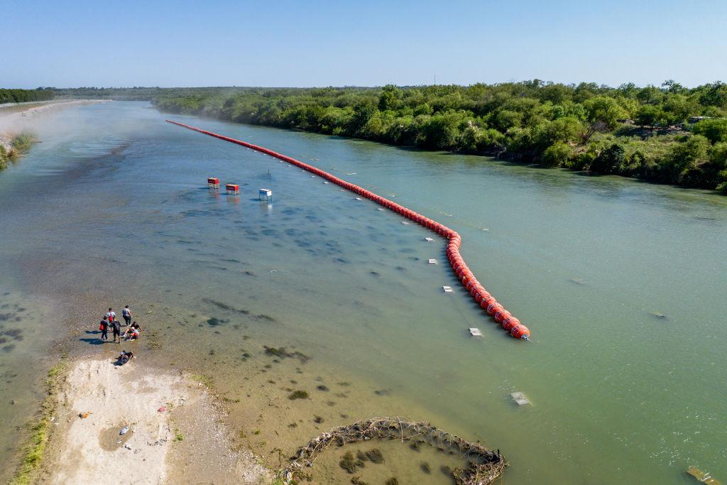 Una familia migrante se encuentra con la barrera de boyas en el río Bravo.