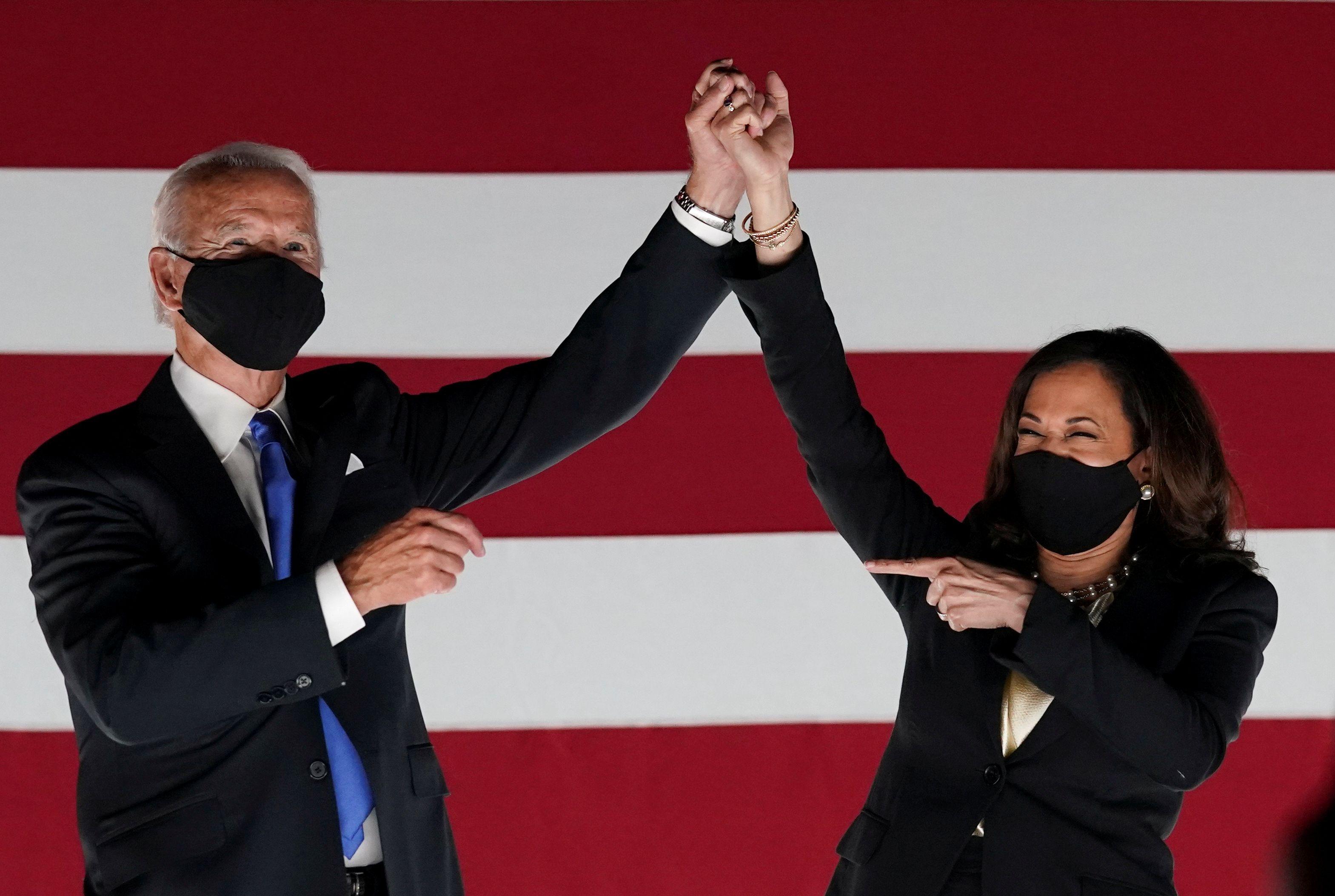 Joe Biden e a senadora Kamala Harris comemoram em frente ao Chase Center, ambos usando máscaras de proteção 