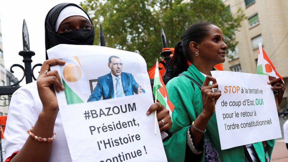 متظاهرون يحملون لافتات وأعلام النيجر أثناء تجمعهم خارج سفارة البلاد في باريس دعما للرئيس محمد بازوم