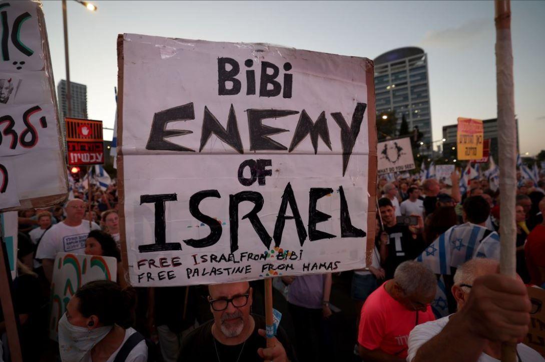 متظاهر إسرائيلي يحمل يافطة مكتوب عليها نتنياهو عدو إسرائيل