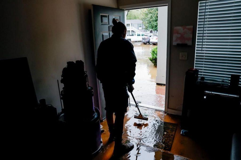 A man drains the water that flooded his house through the front door. 