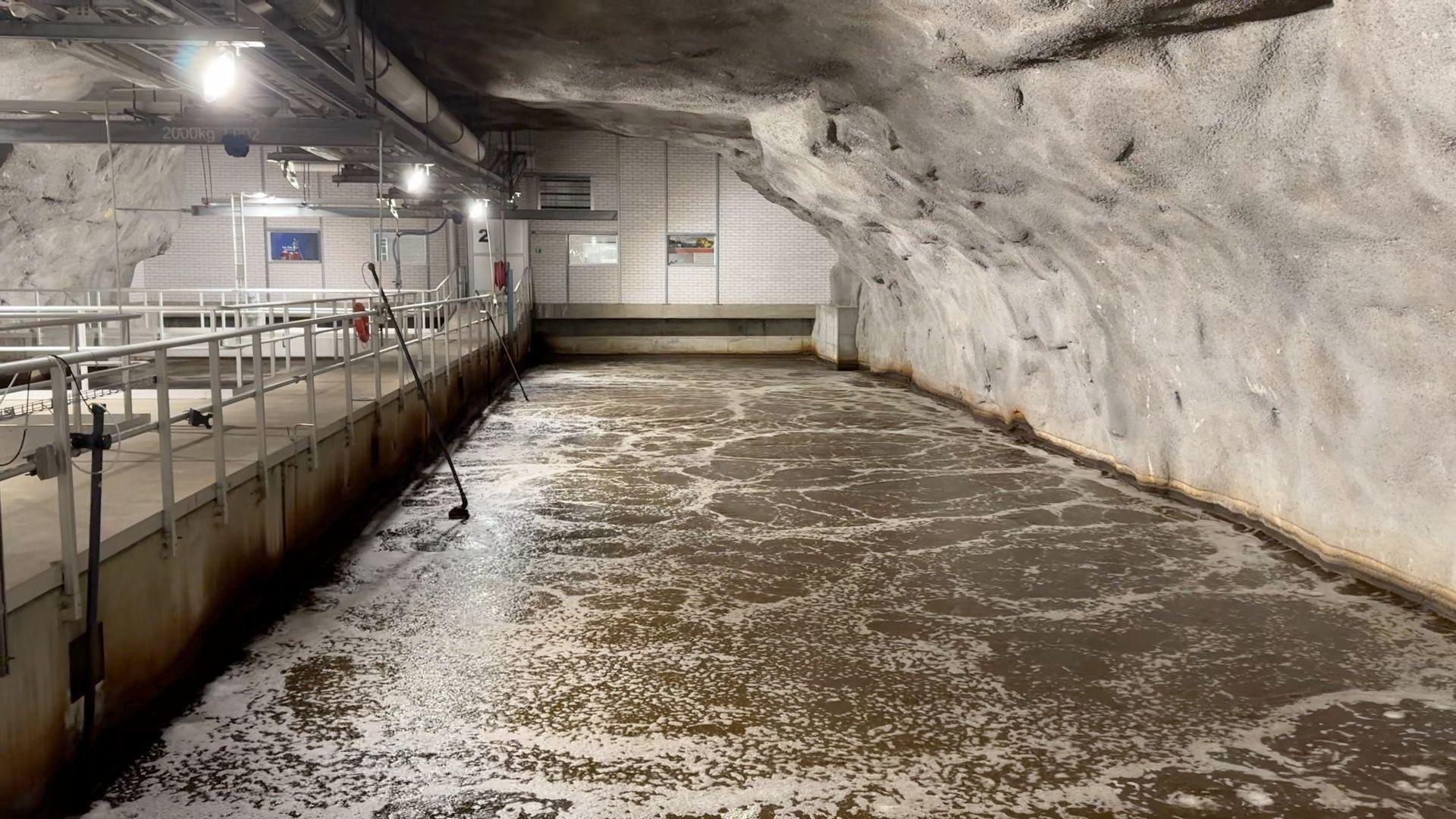 El agua fluye a través de un túnel subterráneo, con un puente para peatones a la izquierda.