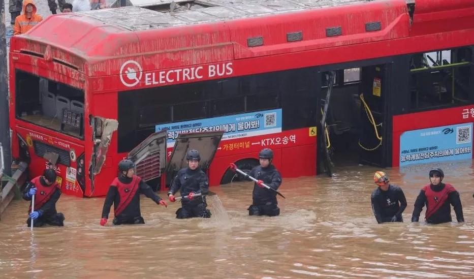عمال إنقاذ في الصورة أمام حافلة يشاركون في عملية بحث وإنقاذ بالقرب من نفق.