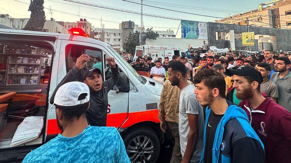 Dezenas de pessoas se reúnem em torno de uma ambulância danificada em um suposto ataque israelense em frente ao hospital Al-Shifa, na cidade de Gaza, em 3 de novembro de 2023.