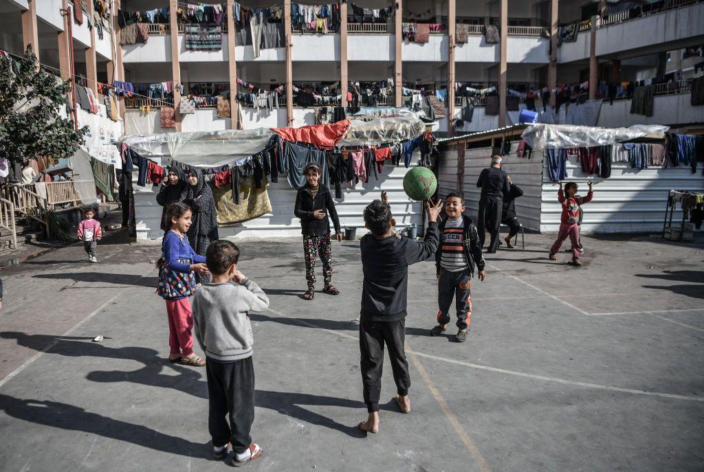 Niños jugando a la pelota en el patio de una escuela convertida en refugio
