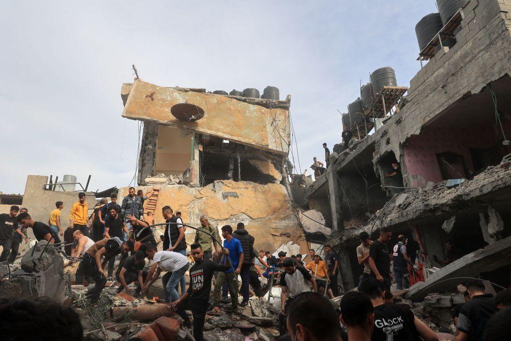 Una multitud buscando sobrevivientes entre las ruinas de un edificio bombardeado.