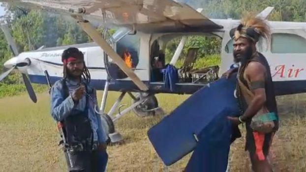 Dua anggota TPNPB-OPM berdiri di depan pesawat Susi Air yang dibakar setelah penyanderaan Kapten Philip Max Mehrtens