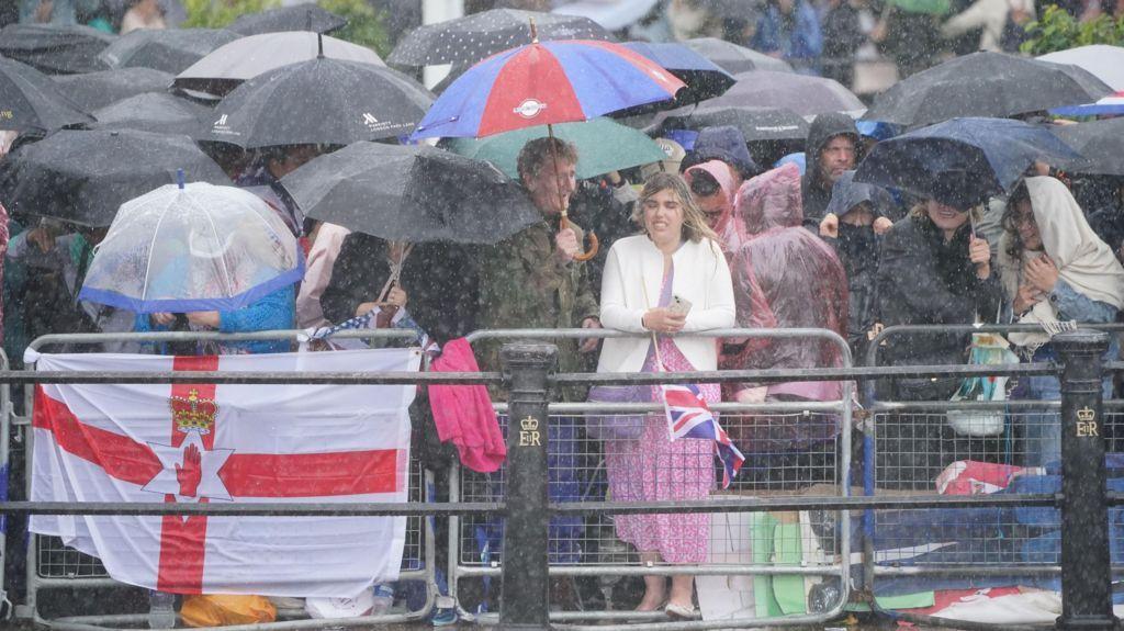 Pessoas sob guarda-chuvas em meio à chuva e vento