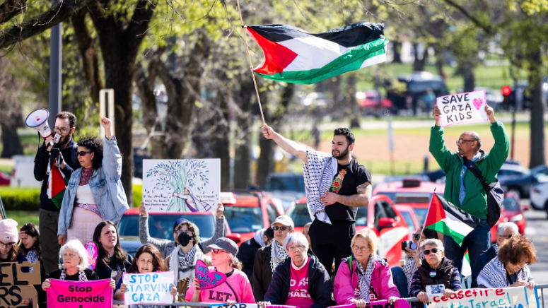 متظاهرون يحملون الأعلام واللافتات الفلسطينية.