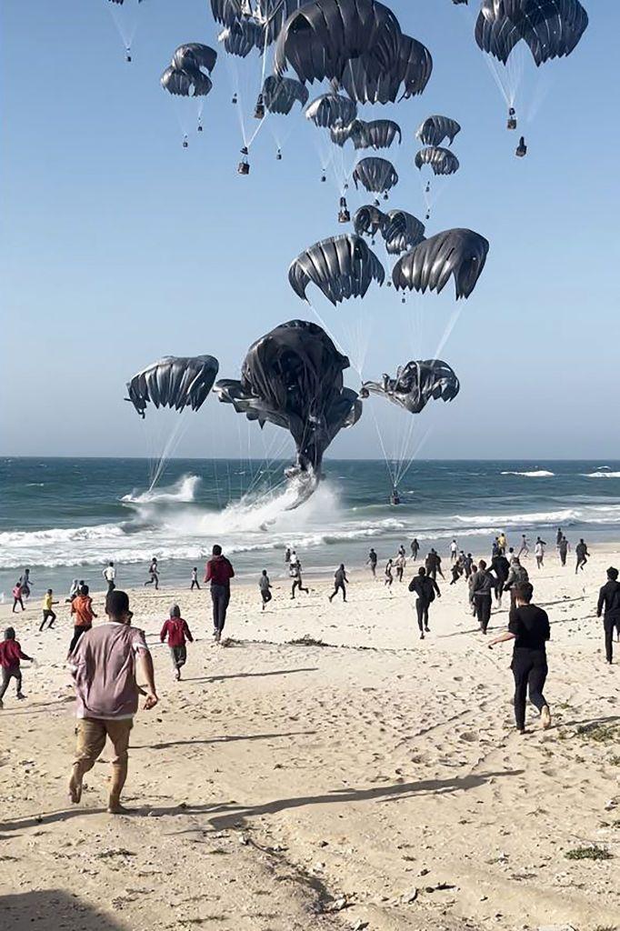Palestinos corriendo al mar para recoger los paquetes con alimentos lanzados desde el aire.