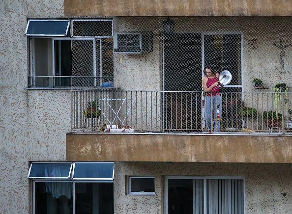 Mulher bate em uma panela na varanda