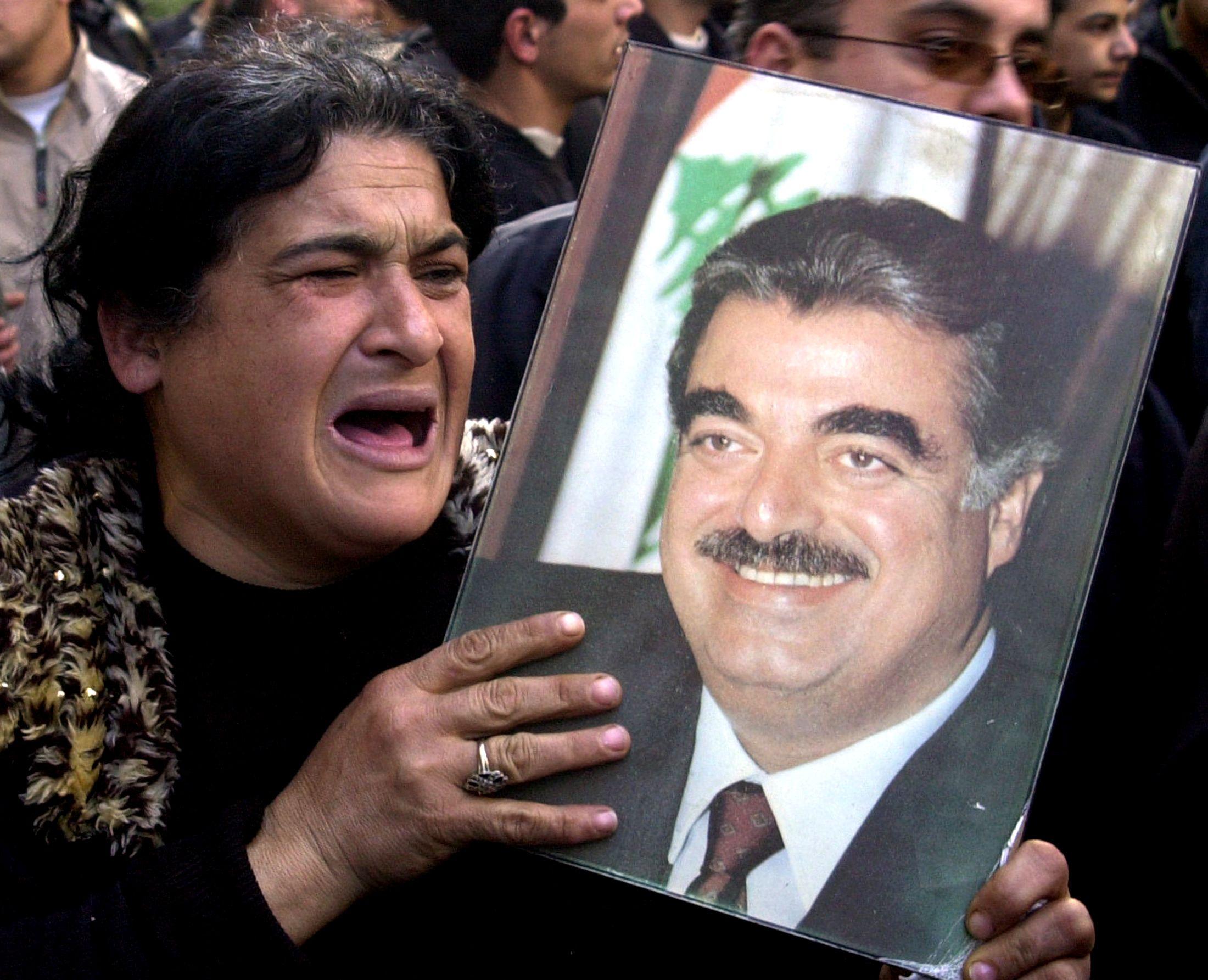 سيدة لبنانية تبكي وهي تحمل صورة رفيق الحريري خلال مظاهرة في بيروت في فبراير/شباط عام 2005