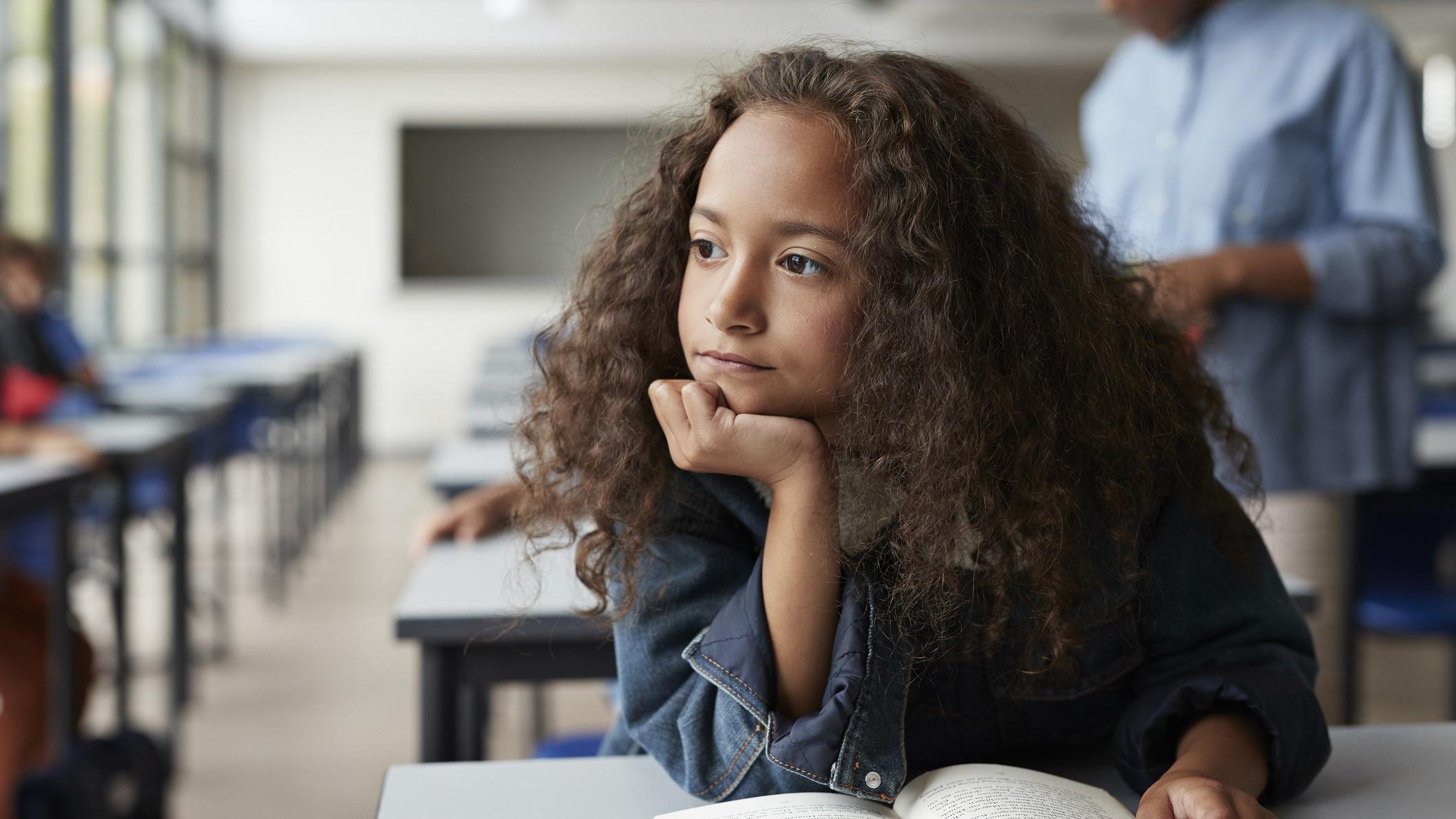 Una niña distraida en clase.