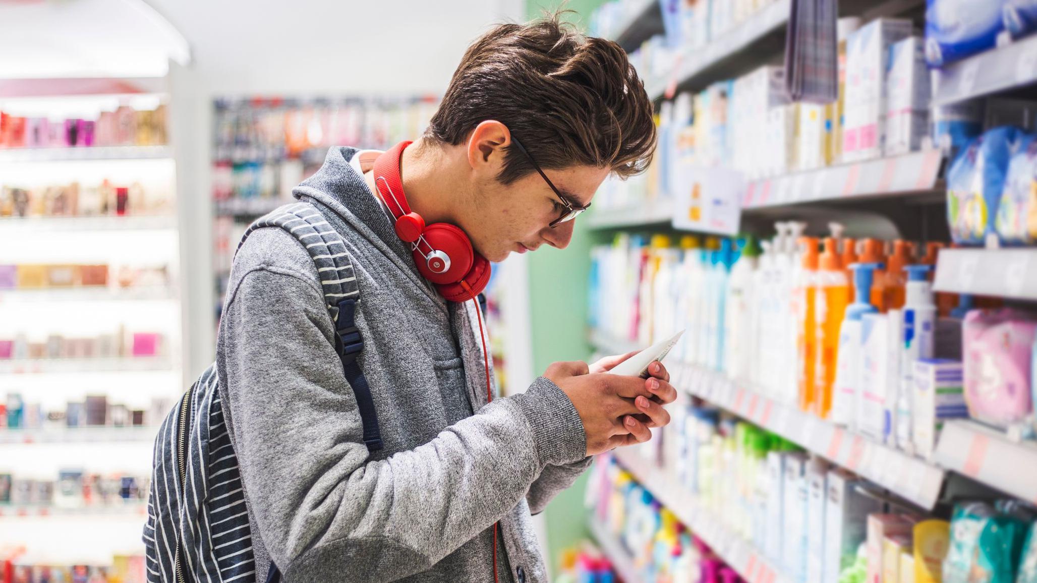 Un joven mira un producto en una farmacia. 