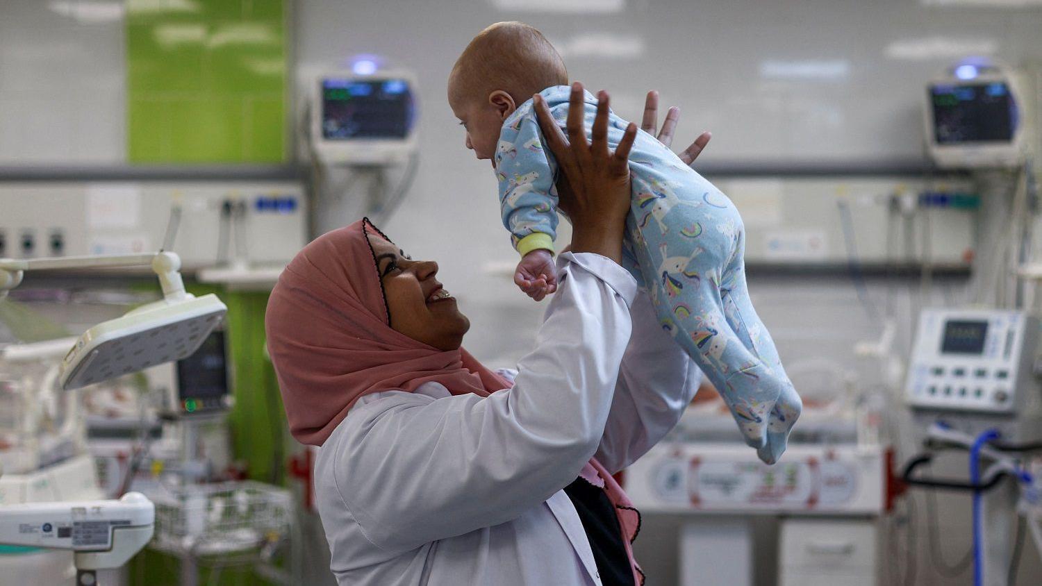 ممرضة تحمل طفلا حديث الولادة في غزة