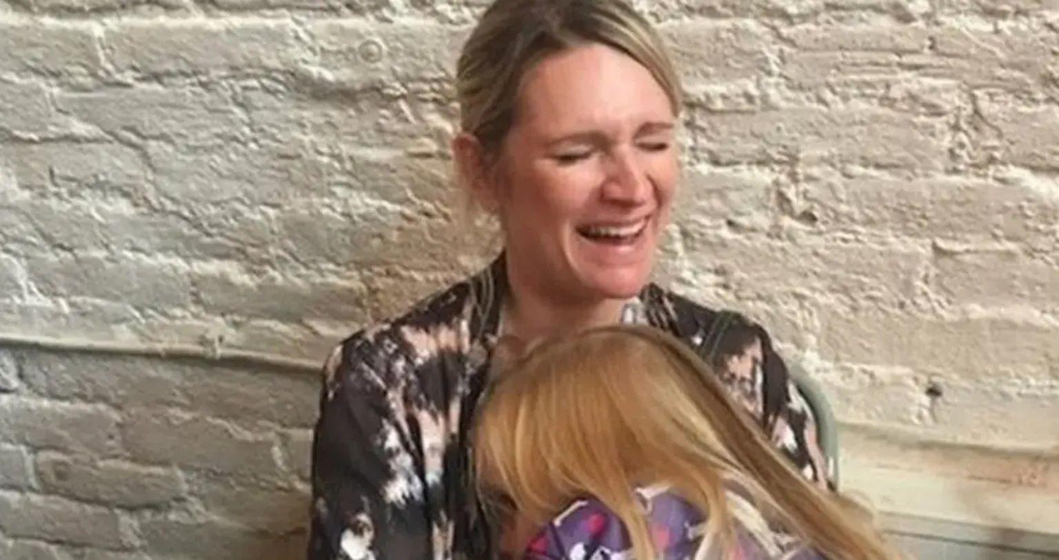 Deb con una de sus hijas, con una gran sonrisa en su cara.