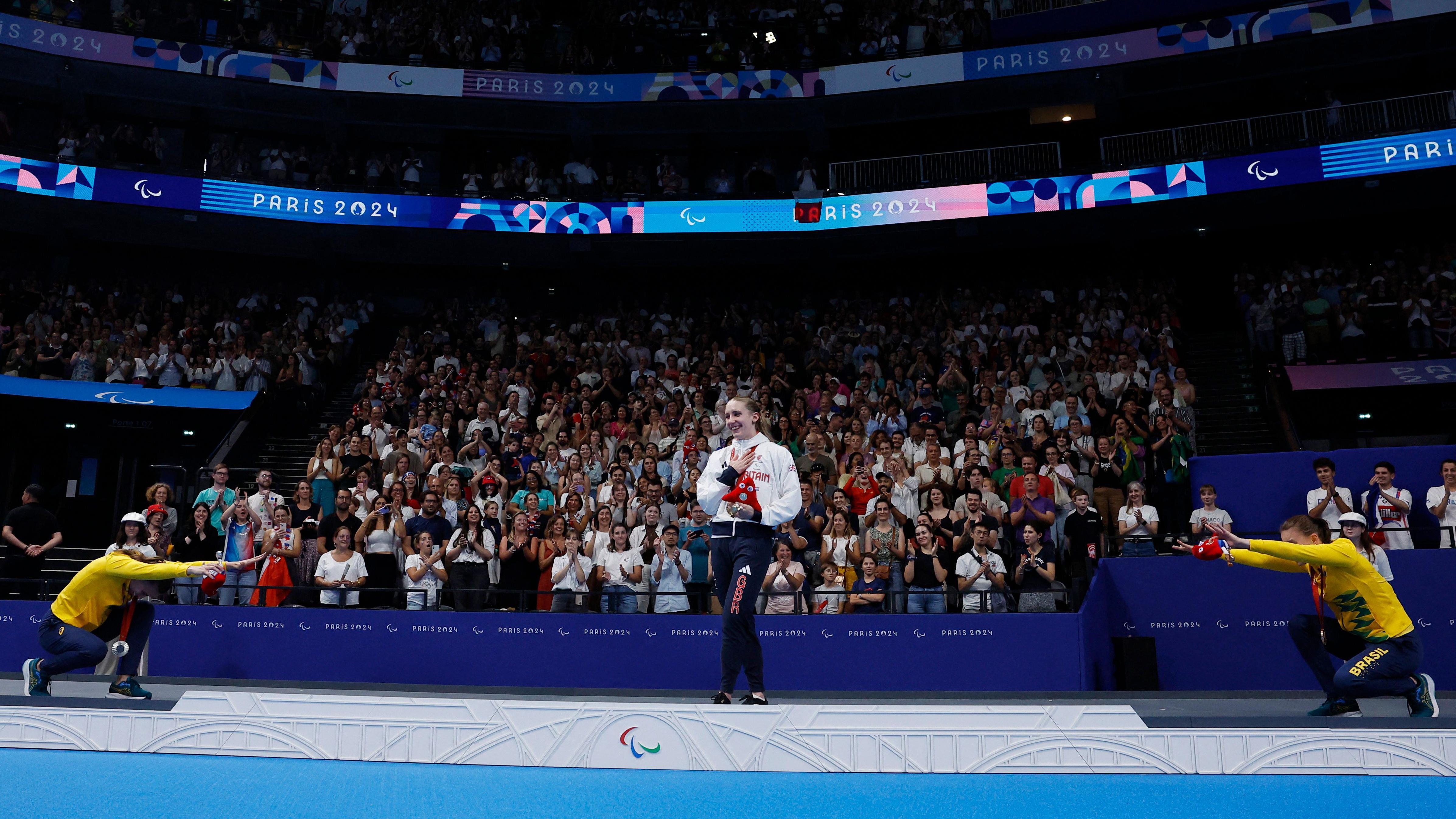 Debora e Beatriz Borges Carneiro saúdam a vencedora da medalha de ouro nos 100 metros peito, a britânica Louise Fiddes