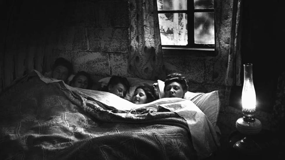 Una madre durmiendo exhausta junto a cuatro hijas en una misma cama tras pasar un día recogiendo lúpulo