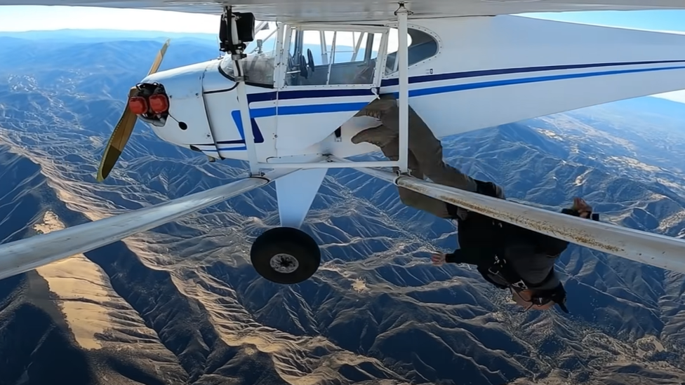 Trevor Jacob saltando de cabeça para fora de seu avião com as montanhas Los Padres abaixo dele