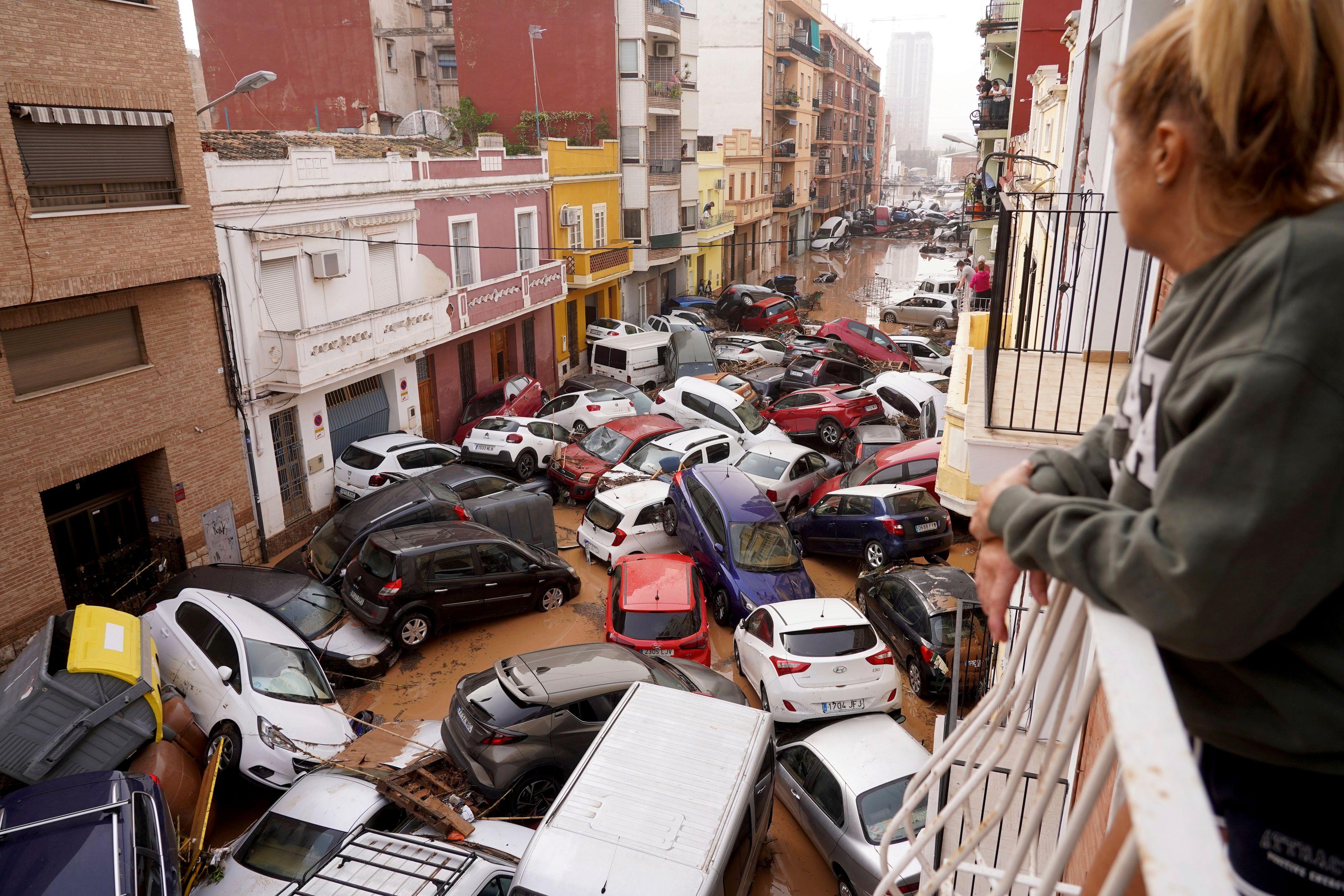 Uma mulher olha de sua varanda para os veículos empilhados na rua durante as enchentes em Valência, em 30 de outubro de 2024.