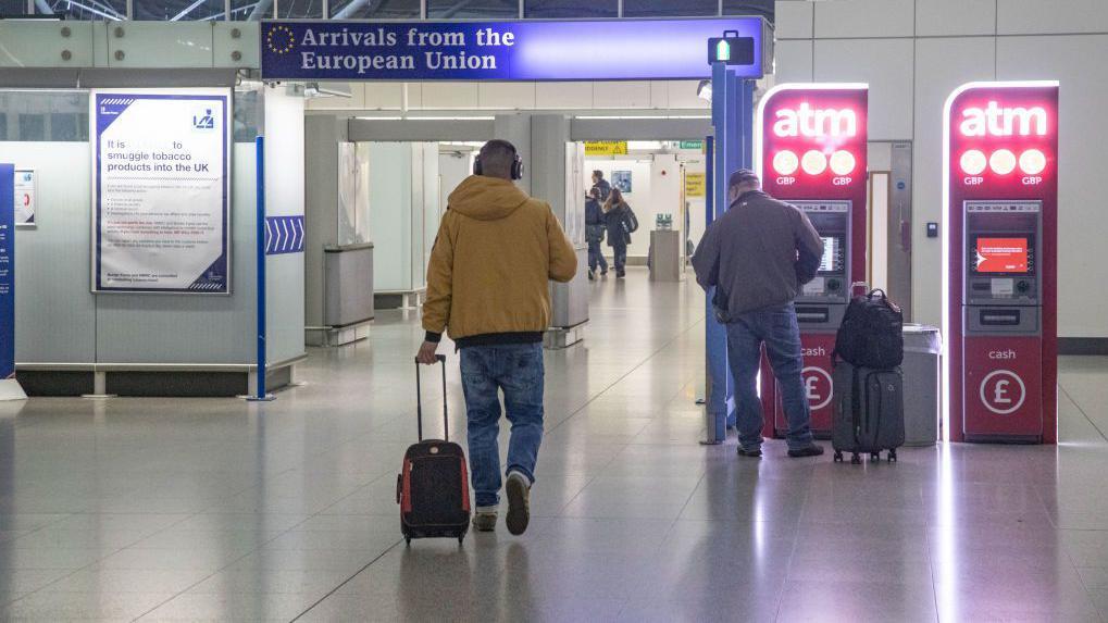 Foto de uma pessoa andando por trás em um aeroporto. 