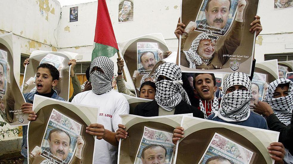 أعضاء فلسطينيون من كتائب شهداء الأقصى يلوحون بصورة الرئيس الراحل عرفات والبرغوثي في قرية روجيب جنوبي نابلس - 2004