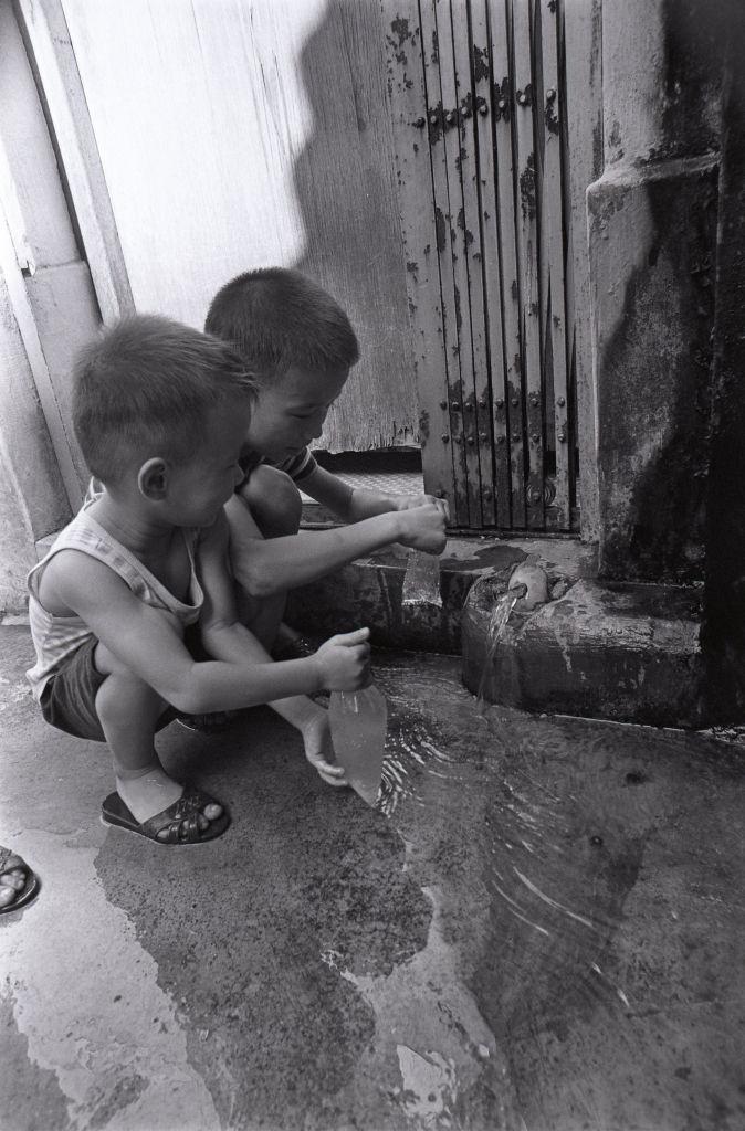 Dos niños preparan bombas de agua en la calle en Kowloon