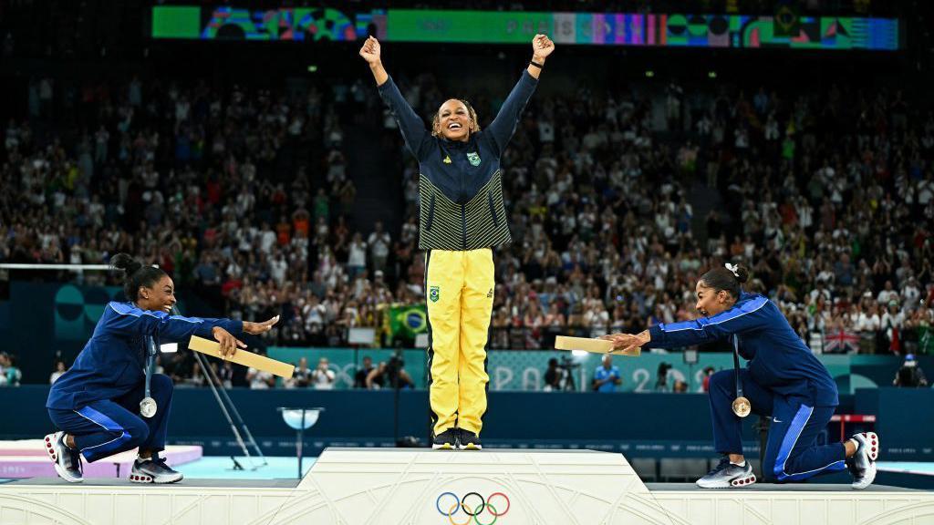 Simone Biles (plata) y Jordan Chiles (bronce) se rinden a los pies de Andrade tras la final de la prueba de suelo femenina de gimnasia artística.